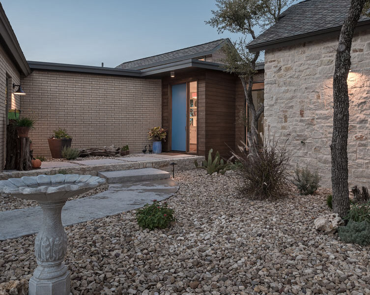 A stone wall and gravel pathway in front of a house.