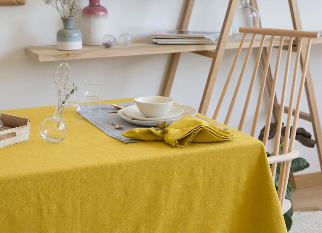 A table with a yellow cloth and a cup on it