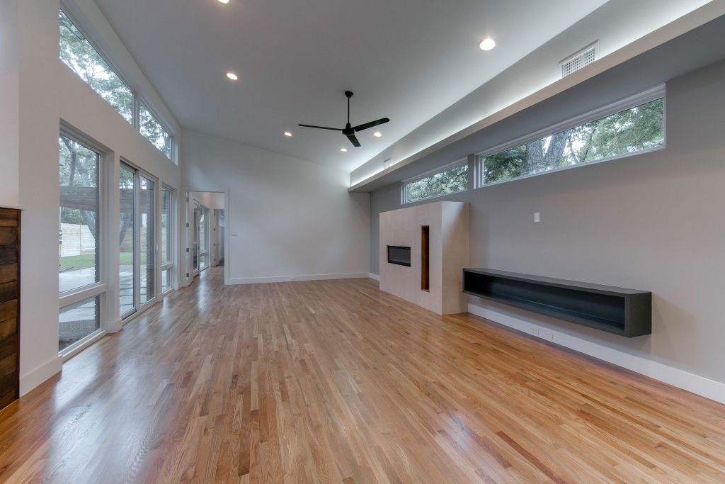 A large room with hard wood floors and windows.