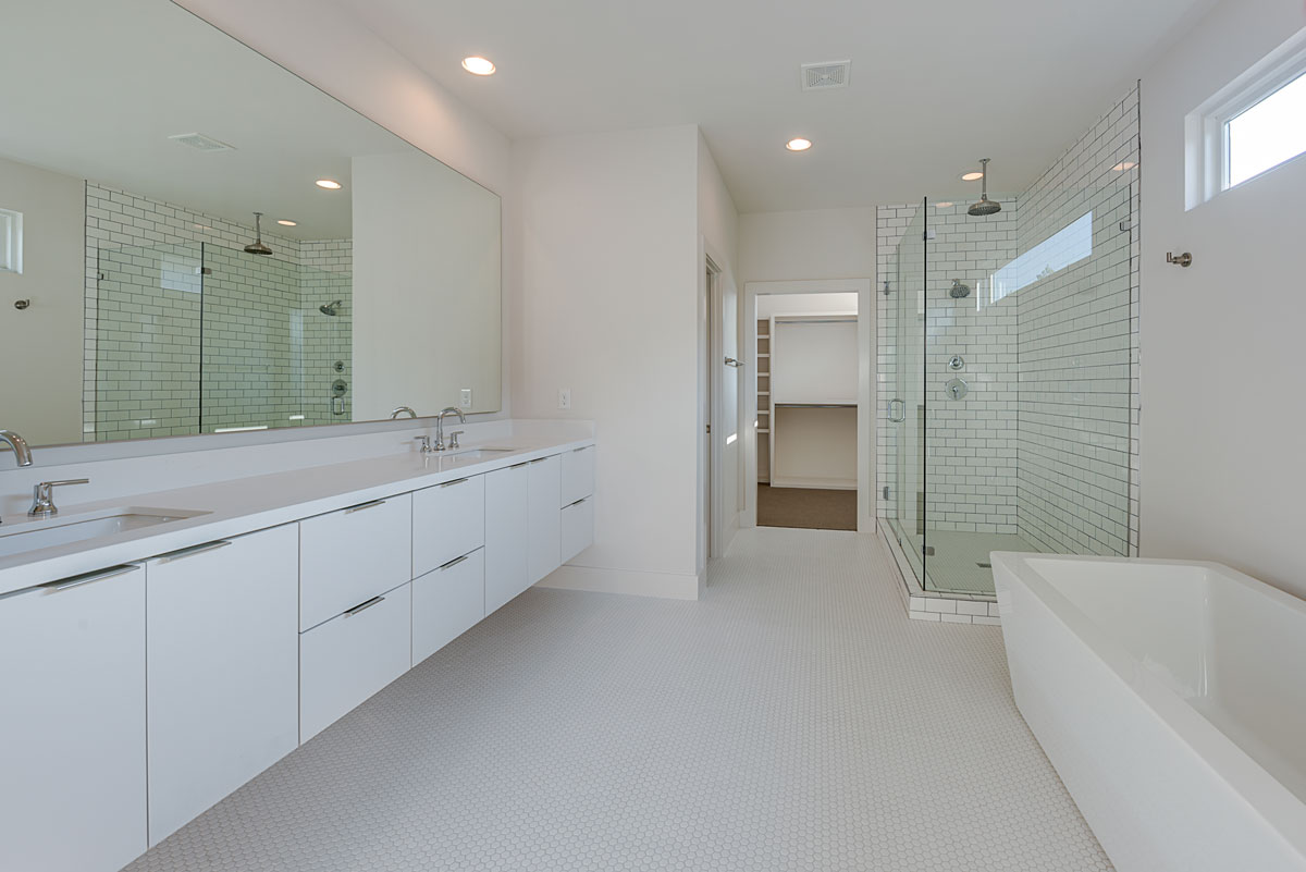 A large bathroom with white cabinets and a glass shower.