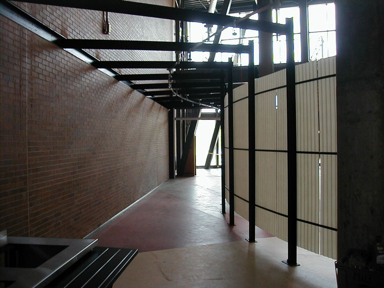 A hallway with metal railings and brick walls.